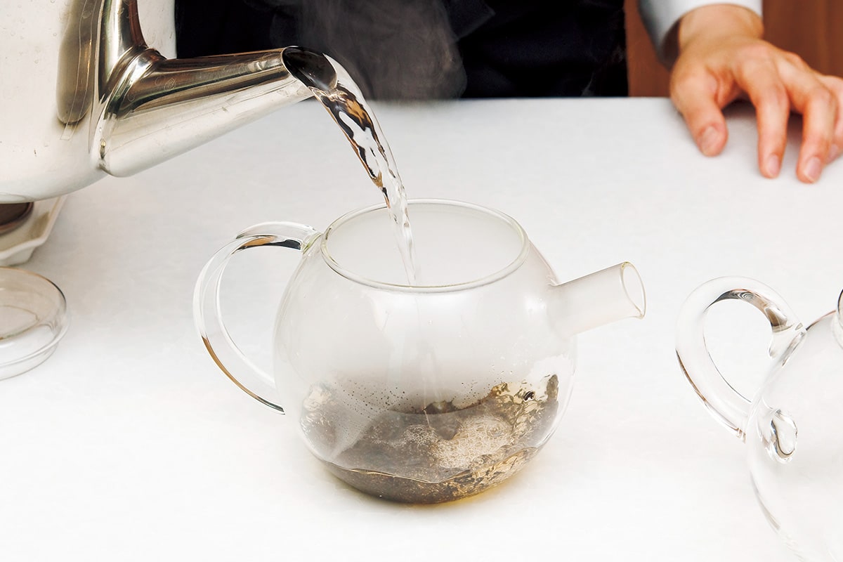 温めたポットに茶葉を入れ熱湯を注ぐ様子