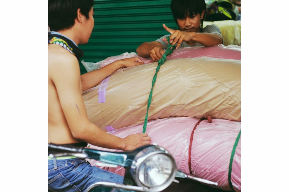 バンコクでベスパに荷物を積む人々