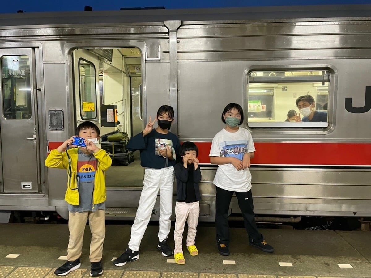 JR根室本線、通称・花崎線の前で写真を撮るライター・村岡俊也と写真家・平野太呂さんの子供たち