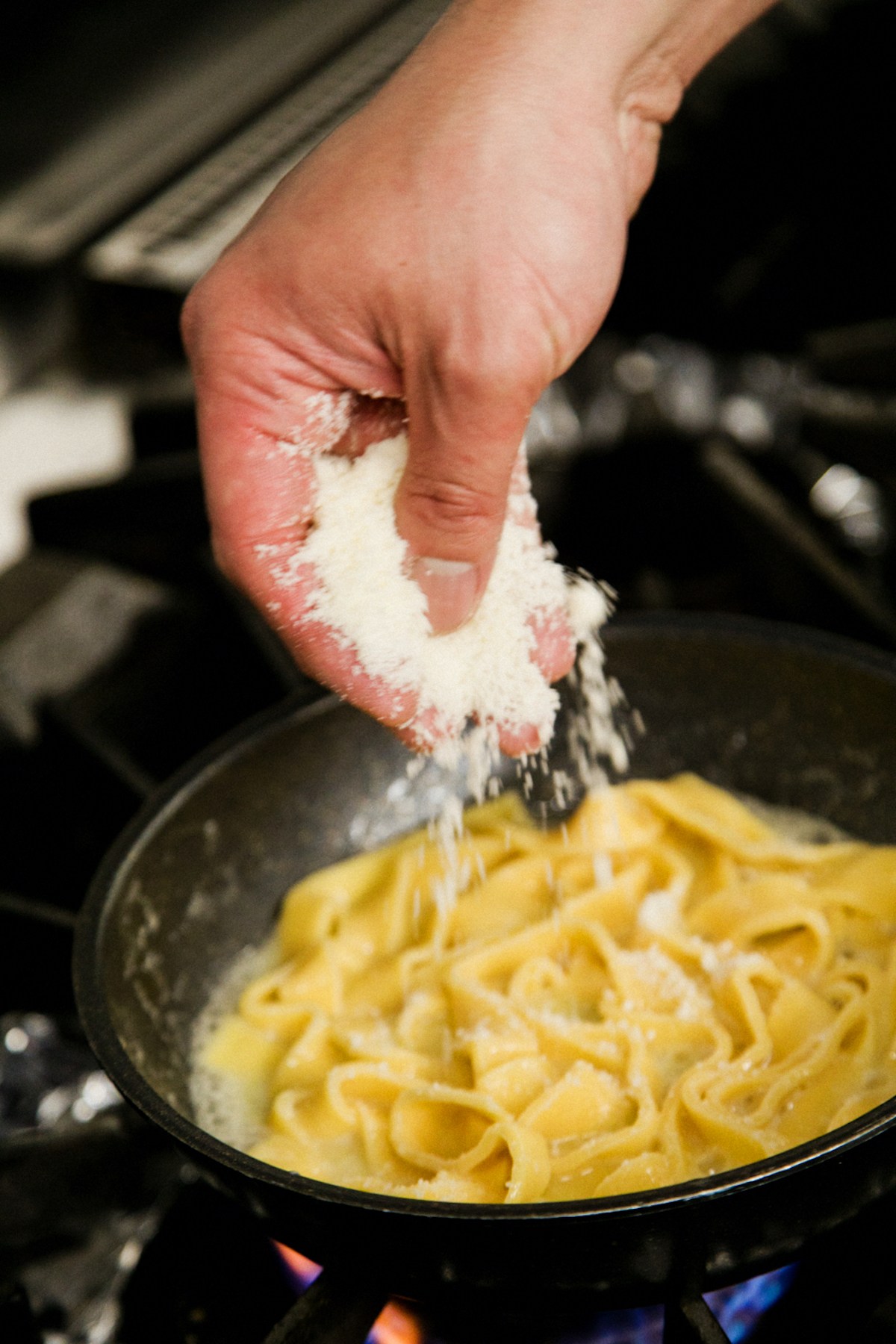 すりおろしたグラナパダーノチーズをパスタに加える
